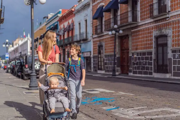 Meksika, Puebla 'nın renkli sömürge sokaklarında yürümekte olan küçük çocukları ve ergen çocuklarıyla birlikte anne turist. Seyahat, kültürel keşif ve canlı mimari konsepti..