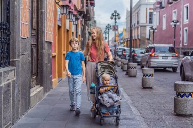 Meksika, Puebla 'nın renkli sömürge sokaklarında yürümekte olan küçük çocukları ve ergen çocuklarıyla birlikte anne turist. Seyahat, kültürel keşif ve canlı mimari konsepti..
