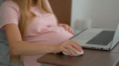 8.-9. ayındaki hamile kadın laptopuyla yataktan çalışıyor, iş ve hamileliği dengeliyor. Uzaktan çalışma, verimlilik ve doğum öncesi bakımı yönetmek