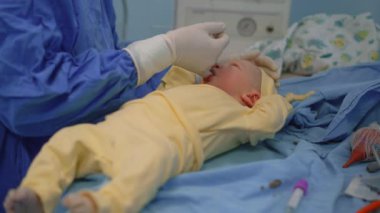 Yeni doğmuş bir bebek, doğumdan hemen sonra bir çocuk doktoru tarafından bir ameliyathanede muayene edilir. Hayatlarının ilk anlarında bebek sağlığını ve refahını sağlamak için dikkatli bir sağlık kontrolü.