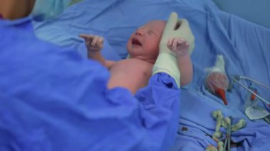 Yeni doğmuş bir bebek, doğumdan hemen sonra bir çocuk doktoru tarafından bir ameliyathanede muayene edilir. Hayatlarının ilk anlarında bebek sağlığını ve refahını sağlamak için dikkatli bir sağlık kontrolü.