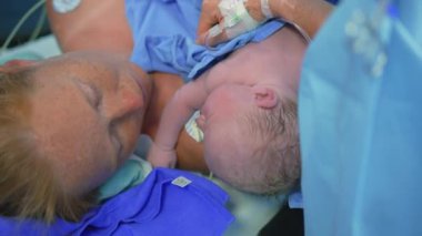 Cerrah sezaryen ameliyatını tamamlarken yeni doğmuş bir bebek anne göğsüne yerleştirilir. Annelik bağı, aşk ve doğumdan sonraki ilk kucaklaşma.
