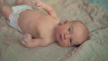 Ağlayan yeni doğmuş bir bebek yatağa uzanır, rahatsızlığını ya da ilgiye olan ihtiyacını ifade eder. Yaşamın ilk günlerinde gerekli şefkati ve bakımı yansıtan samimi bir an.