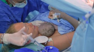 Cerrah sezaryen ameliyatını tamamlarken yeni doğmuş bir bebek anne göğsüne yerleştirilir. Annelik bağı, aşk ve doğumdan sonraki ilk kucaklaşma.