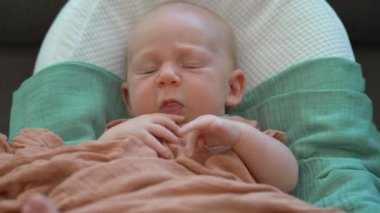 Yeni doğmuş bir bebek, yumuşak çarşafla örtülü, rahat bir bebek kozasında huzur içinde yatar. Huzurlu ve rahat bir an. Bebeklerin ilk günleri için rahatlık ve ilgiyi ön plana çıkarıyor.