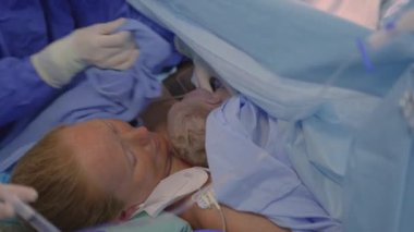Cerrah sezaryen ameliyatını tamamlarken yeni doğmuş bir bebek anne göğsüne yerleştirilir. Annelik bağı, aşk ve doğumdan sonraki ilk kucaklaşma.