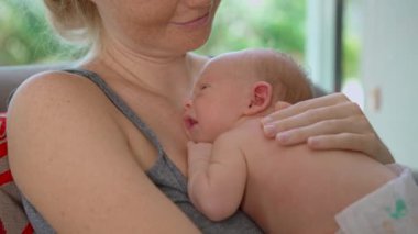 Genç bir anne sevgiyle kucağında küçük bebeğini kucağına alır. Yürek ısıtan bir bağ ve şefkat anını paylaşır. Aşkın güzel bir ifadesi, bağlanma ve anneliğin başlangıcı.