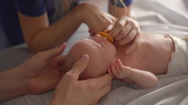 Yeni doğmuş bir bebek ve annesi bir osteopattan sağlık kontrolü ve olası sorunlara karşı nazik bir terapi görürler. Bebek sağlığına, refahına ve erken gelişime odaklanmış bir an.