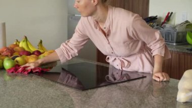 Genç bir kadın mutfak masasını temizliyor, evinde temizlik ve düzen sağlıyor. Basit ama önemli bir ev yapımı, bakım ve düzenli ve davetkar bir yer yaratma anı