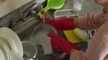 Genç bir kadın mutfakta bulaşıkları yıkıyor, temizlik ve düzene odaklanıyor. Basit ve uyumlu bir ev yapımı, ev bakımı ve düzenli bir ev ortamı.