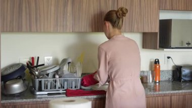 Genç bir kadın mutfakta bulaşıkları yıkıyor, temizlik ve düzene odaklanıyor. Basit ve uyumlu bir ev yapımı, ev bakımı ve düzenli bir ev ortamı.
