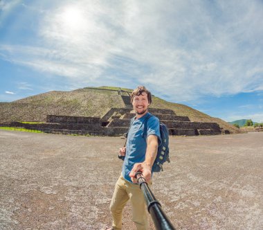 Teotihuacan, Meksika 'yı keşfeden erkek turist. Gündoğumunda eski piramitlerin ve harabelerin içinden tek başına geçen bir gezgin. Kültür mirası, arkeoloji ve Meksika turizmi kavramı.