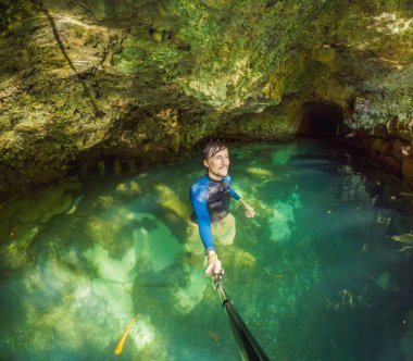 Etrafı doğal güzelliklerle çevrili bir Meksika mezarlığının sularındaki erkek turist. Tropik bir cennette macera seyahati, eko-turizm ve keşif konsepti.