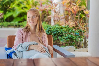 Bir anne, bebeğini rahat bir kafede emzirir. Sıradan, halka açık bir ortamda doğal ve besleyici bir anı kucaklar. Bu samimi sahne modern ebeveynliği, annelik sevgisini ve güzelliği yansıtıyor.