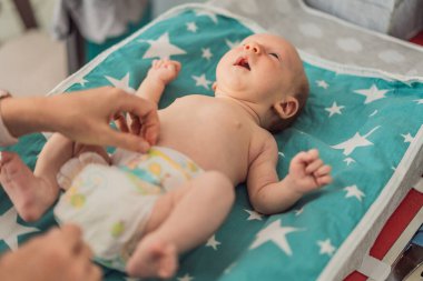 Genç anne evde bebek bezini değiştiriyor. Bakıcı anne yeni doğan çocuğa hijyen uygulaması yapıyor. Ebeveynlik, bebek bakımı ve erken annelik kavramı..