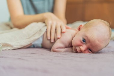 Bir anne, bir aylık bebeğine banyodan sonra nazikçe bebek yağı ile masaj yapar. Bu hassas an, ebeveyn ve çocuk arasındaki bağı, rahatlamayı, bebek bakımını ve cildin önemini ön plana çıkarıyor.