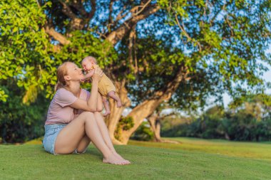 Genç anne, bir aylık bebeğiyle parkta huzurlu bir yürüyüşün tadını çıkarıyor. Annelik, bağlılık ve açık hava aile zaman kavramı..