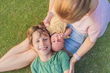 Young mother, teenage son, and one-month-old baby enjoying quality family time in the park. Multigenerational bonding and outdoor family love concept. clipart