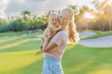 Genç anne, bir aylık bebeğiyle parkta huzurlu bir yürüyüşün tadını çıkarıyor. Annelik, bağlılık ve açık hava aile zaman kavramı..
