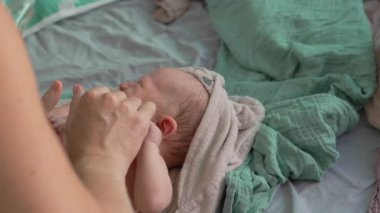 Banyodan sonra anne yeni doğan bebeğine nazikçe masaj yapar ve bebekler için cilt yağı sürer. Bebek konforu, rahatlama ve sağlıklı cilt için hassas bir bağ ve bakım anı.