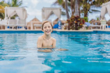 Genç bir çocuk yemyeşil sularla çevrili tropik bir havuzda neşeyle yüzüyor. Canlı sahne, yaz eğlencesinin, maceranın ve kaygısız çocukluk anılarını canlandırır.