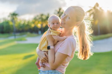 Genç anne, bir aylık bebeğiyle parkta huzurlu bir yürüyüşün tadını çıkarıyor. Annelik, bağlılık ve açık hava aile zaman kavramı..
