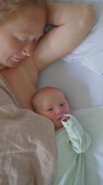 Dikey video. Genç bir kadın hastane yatağında, yanında yeni doğmuş çocuğuyla yatıyor. Hassas ve duygusal bir bağ kurma, aşk ve klinik ortamda anneliğin başlangıcı..