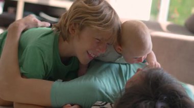 Bir baba, ağabey ve yeni doğan bebekleri yerde yatarken harika vakit geçiriyorlar. Güzel bir aile sevgisi, şefkat ve bağlılık anı huzurlu ve huzurlu bir ortamda.