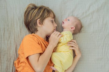 Genç bir çocuk ve yeni doğan erkek kardeşi yumuşak bir muslin battaniyeye uzanıp kardeşçe bir anı paylaşıyorlar. Yürek ısıtan bir kardeş sevgisi, bağlılık ve hayat boyu sürecek bir bağlantının başlangıcı..