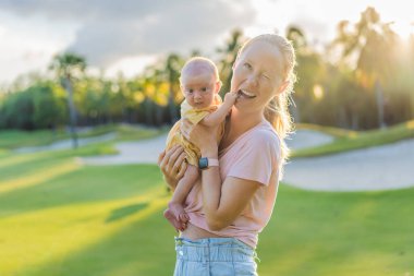 Genç anne, bir aylık bebeğiyle parkta huzurlu bir yürüyüşün tadını çıkarıyor. Annelik, bağlılık ve açık hava aile zaman kavramı..