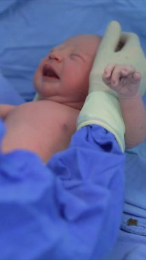 Yeni doğmuş bir bebek, doğumdan hemen sonra bir çocuk doktoru tarafından bir ameliyathanede muayene edilir. Hayatlarının ilk anlarında bebek sağlığını ve refahını sağlamak için dikkatli bir sağlık kontrolü.