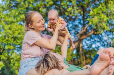 Genç bir anne, genç bir oğul ve bir aylık bir bebek parkta kaliteli vakit geçiriyorlar. Çoklu nesiller arası bağ ve açık havada aile sevgisi kavramı.
