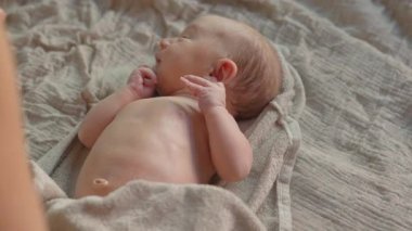 Banyodan sonra anne yeni doğan bebeğine nazikçe masaj yapar ve bebekler için cilt yağı sürer. Bebek konforu, rahatlama ve sağlıklı cilt için hassas bir bağ ve bakım anı.