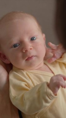 Genç bir baba yeni doğmuş bebeğini yatakta otururken kollarında tutar. Doğal ışıkta huzur, sevgi, bağ ve sıcaklık dolu bir an.