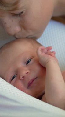 Sevgi dolu bir ağabey, bebek kozasında dinlenen küçük kardeşini nazikçe öper. Şefkatli ve yürek ısıtan bir kardeşlik anı, aile sevgisi ve yeni bir hayata kucak açmanın sevinci.