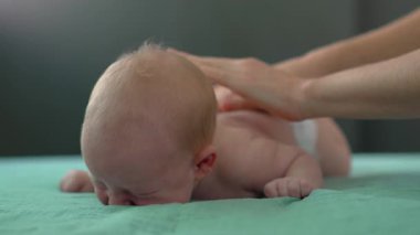 Anne yeni doğanları nazikçe okşuyor, rahatlatıcı bir masaj yapıyor. Bebek bakımı, bağlanma ve annelik kavramı. Yavaş çekim videosu
