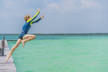 Çocuk Quintana Roo, Meksika 'da büyüleyici bir turkuaz lagünün içine atlıyor. Neşeli yaz macerası ve tropikal seyahat konsepti.