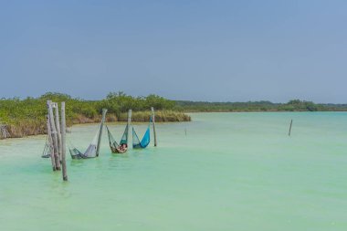 Anne ve oğlu Meksika 'da bir hamakta turkuaz gölün üzerinde dinleniyorlar. Aile bağları ve tropik kaçış konsepti.