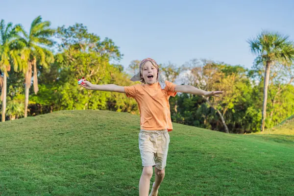 Pilot şapkası takan bir çocuk oyuncak bir uçakla çimlerde koşuyor, maceralar hayal ediyor. Çocukluk, hayal gücü ve özgürlük kavramı..