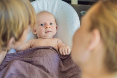 Anne ve büyük oğul, yeni doğan bebeklerine sıcak bir yuvada hayranlık duyuyorlar. Aile bağları ve kardeş sevgisi kavramı.