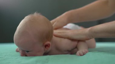 Anne yeni doğanları nazikçe okşuyor, rahatlatıcı bir masaj yapıyor. Bebek bakımı, bağlanma ve annelik kavramı. Yavaş çekim videosu