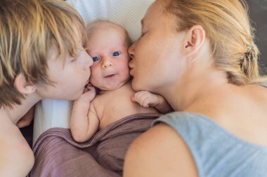 Anne ve büyük oğul, yeni doğan bebeklerine sıcak bir yuvada hayranlık duyuyorlar. Aile bağları ve kardeş sevgisi kavramı.