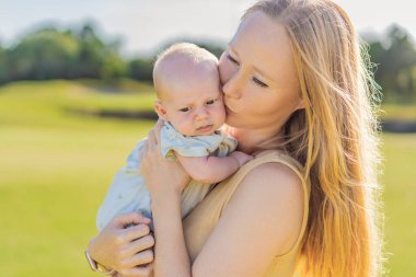 Anne ve yeni doğmuş bebek parkta bir çayırda. Doğadaki hassas bağ anı. Ebeveynlik, sevgi ve aile bağları kavramı.