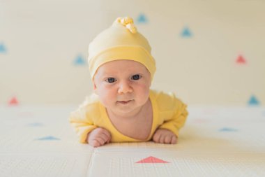 Bir aylık bir bebek karnının üstünde yatıyor ve tuhaf bir şekilde çevreyi gözlemliyor. Boyun dayanıklılığı, bilişsel gelişim ve erken keşif için bebek midesi zamanı. Ebeveynlik ve yeni doğan büyüme kavramı.