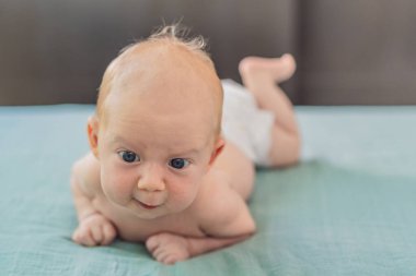 Bir aylık bir bebek karnının üstünde yatıyor ve tuhaf bir şekilde çevreyi gözlemliyor. Boyun dayanıklılığı, bilişsel gelişim ve erken keşif için bebek midesi zamanı. Ebeveynlik ve yeni doğan büyüme kavramı.