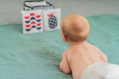 Yeni doğmuş bebek siyah, beyaz ve kırmızı yüksek kontrastlı kartlara bakıyor. Bebek gelişimi için erken görsel uyarılma. Bebek duyusal öğrenme ve bilişsel büyüme kavramı.