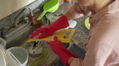 Genç bir kadın mutfakta bulaşıkları yıkıyor, temizlik ve düzene odaklanıyor. Basit ve uyumlu bir ev yapımı, ev bakımı ve düzenli bir ev ortamı.