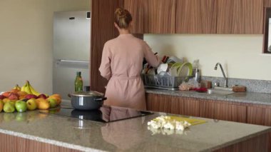 Genç bir kadın mutfakta yemek pişiriyor ve lezzetli bir ev yemeği hazırlamaya odaklanıyor. Sıcacık bir ortamda ev yapımı, yaratıcılık ve aşçılık keyfi.