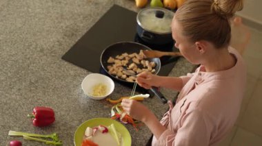 Genç bir kadın mutfakta yemek pişiriyor ve lezzetli bir ev yemeği hazırlamaya odaklanıyor. Sıcacık bir ortamda ev yapımı, yaratıcılık ve aşçılık keyfi.