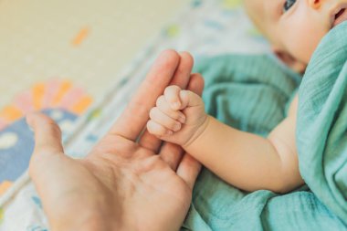 Baba yeni doğmuş bebeklerinin minik ellerini nazikçe tutuyor. Aşk, bağlılık ve ebeveynlik kavramı.
